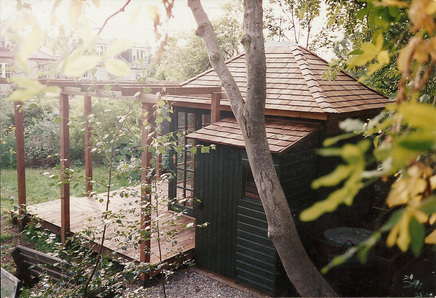 An attractive, small summer house with toolshed attached, deck and pergola