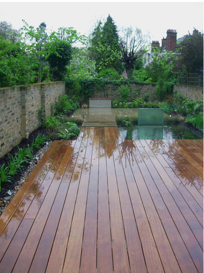 The new garden after planting, showing the Iroko deck, pond and glass water feature, as well as York stone paving.